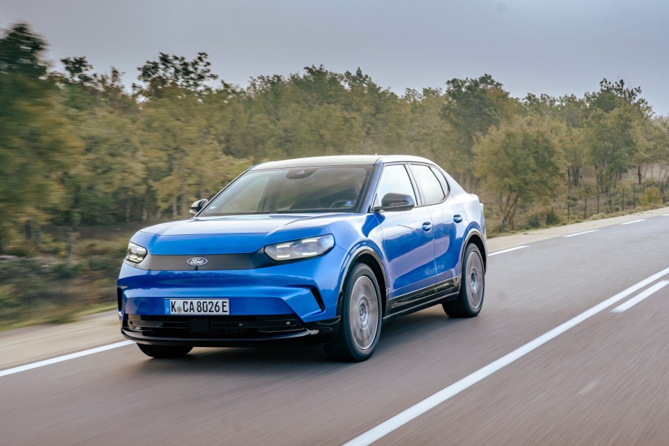 a blue ford car is driving down a road