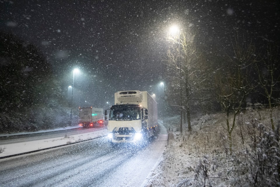 a white truck is driving down a snowy road at night