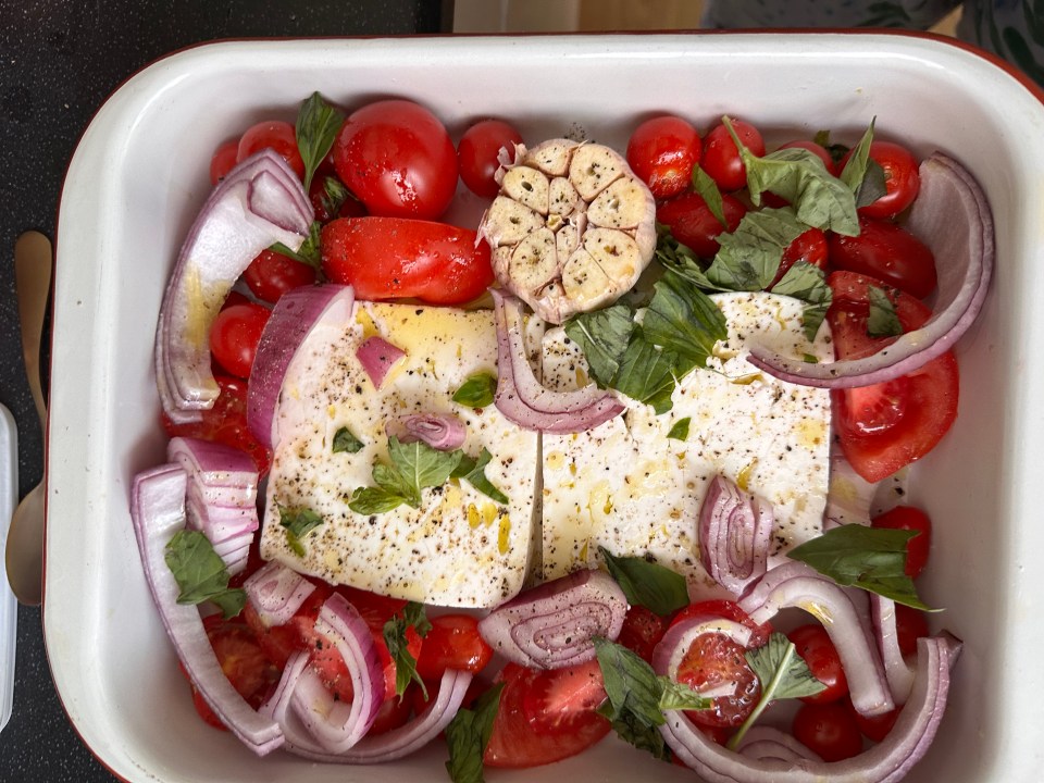 a casserole dish filled with tomatoes onions and feta cheese