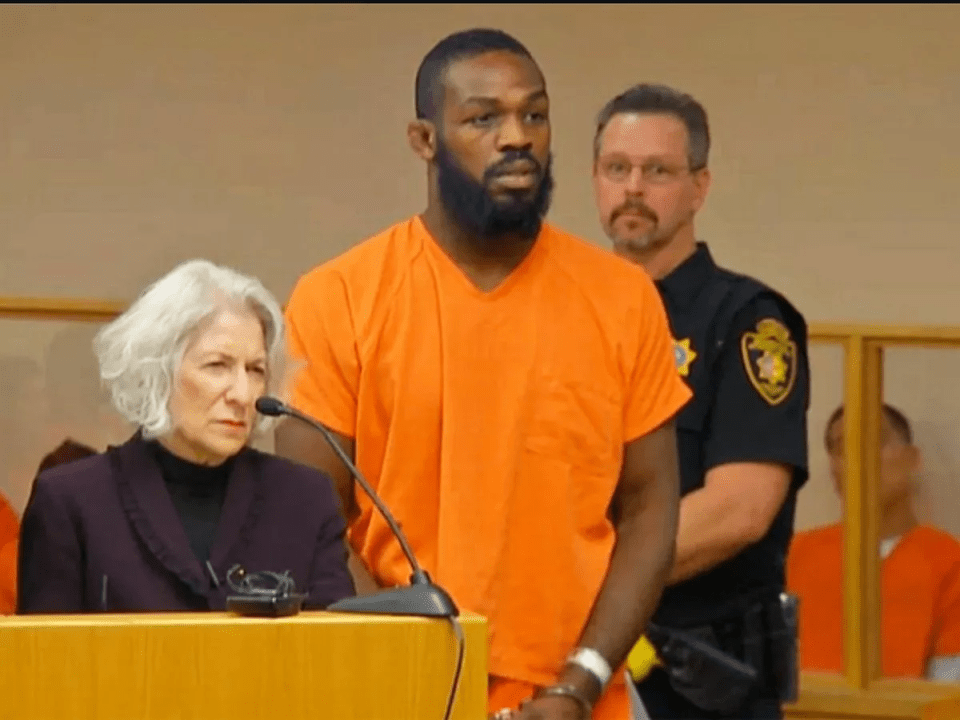 a man in an orange shirt stands in front of a microphone