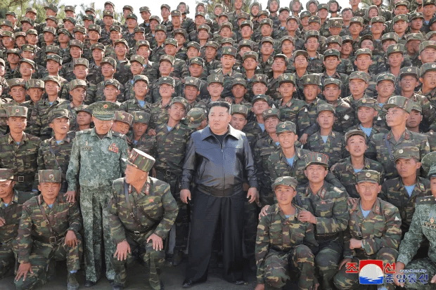 a large group of soldiers are posing for a picture with a korean flag in the background