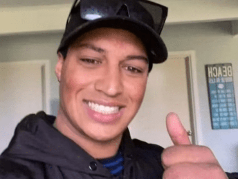 a man wearing a hat and sunglasses gives a thumbs up