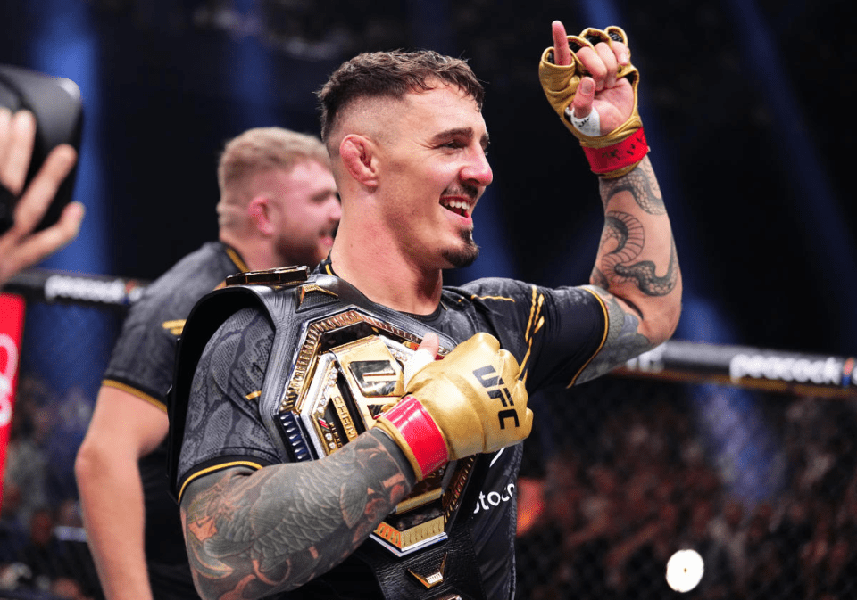 a man wearing a ufc belt and gold gloves
