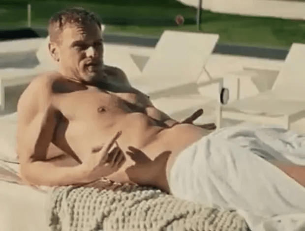 a shirtless man is laying on a lawn chair with a towel around his waist .