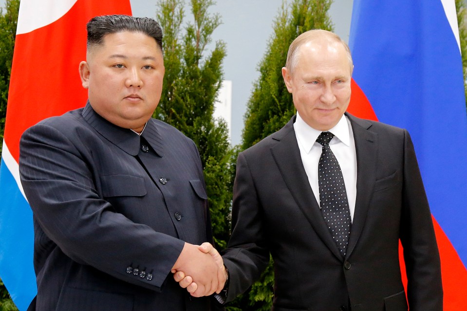 two men shaking hands in front of a red white and blue flag