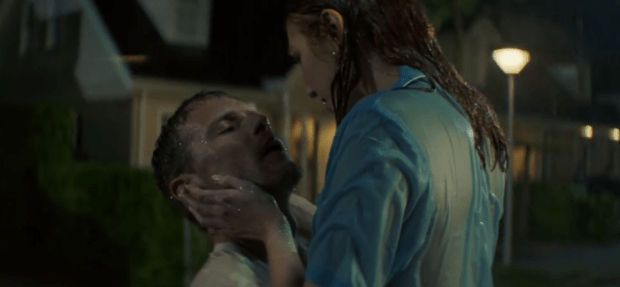 a woman in a blue shirt is holding a man in her arms