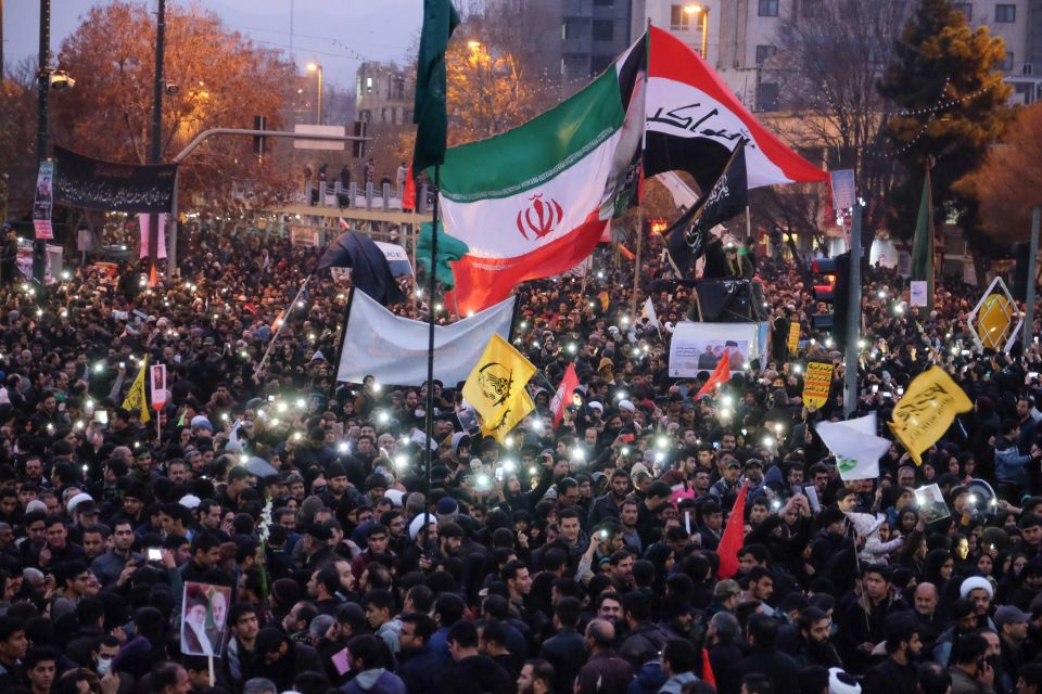 a crowd of people holding flags including one that says ' iran ' on it