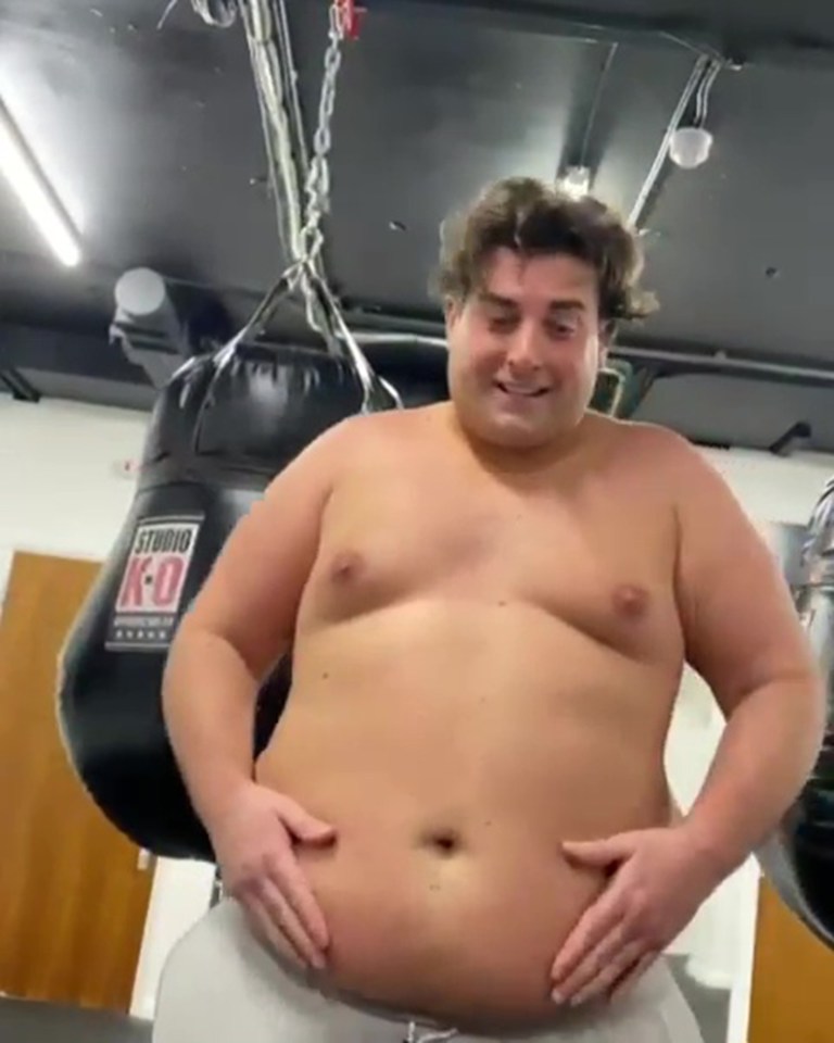 a shirtless man is holding his belly in a gym .