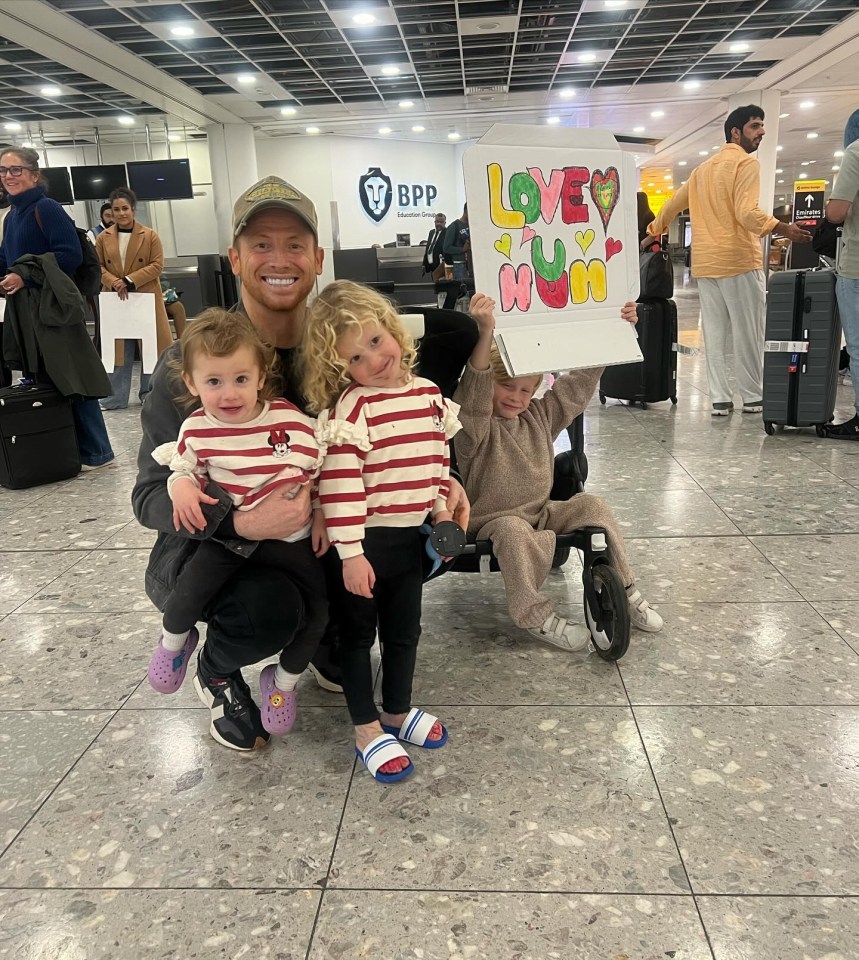 a man is holding three children and holding a sign that says lovely mum