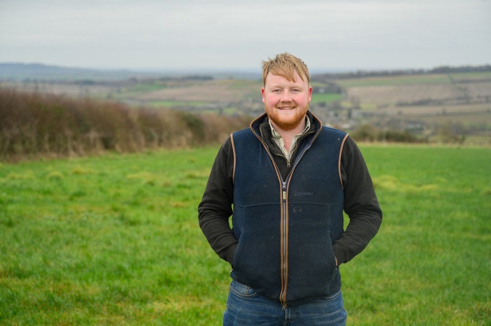 a man standing in a field wearing a columbia vest