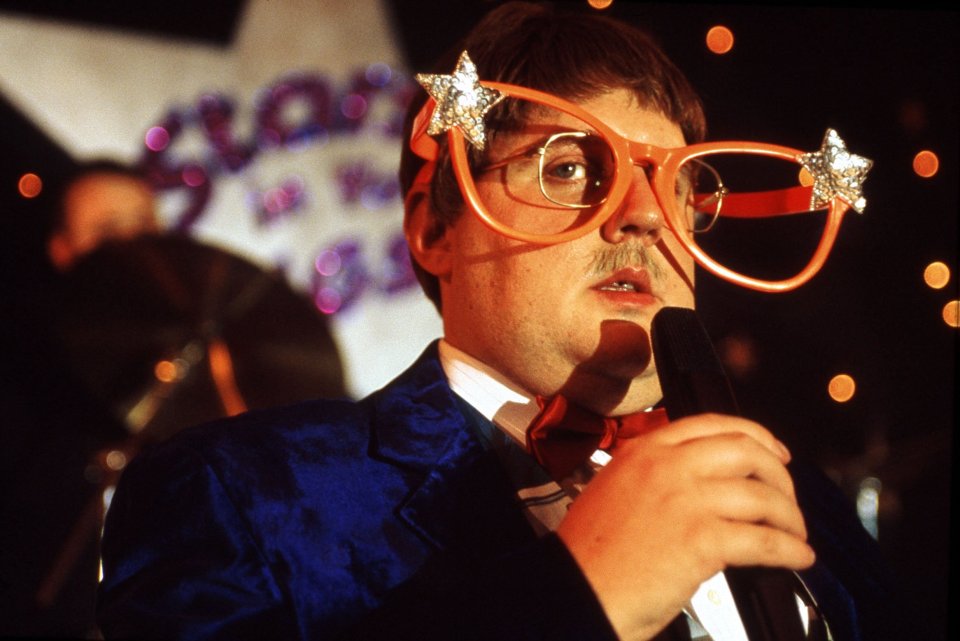 a man wearing glasses with stars on them holds a microphone