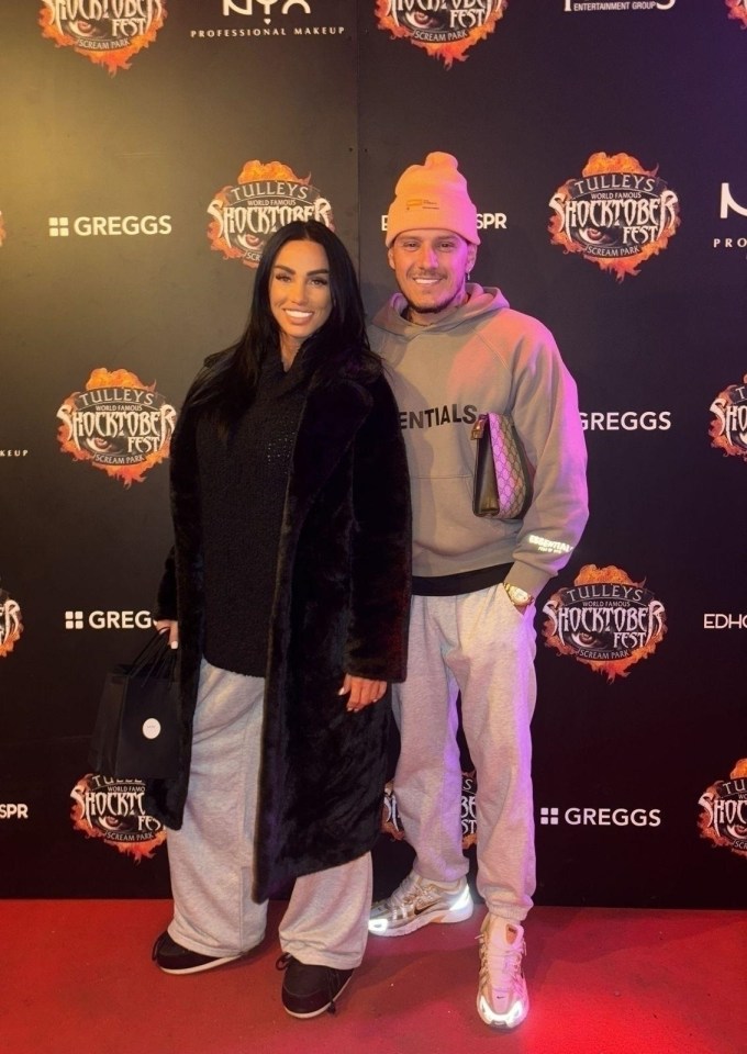a couple standing in front of a wall that says tullys shocktober fest