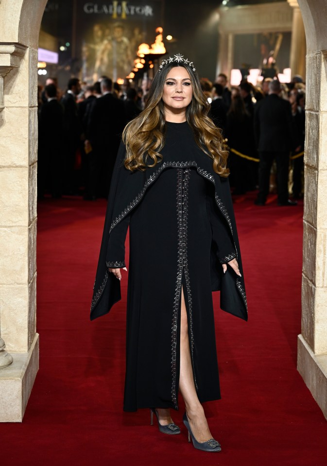 a woman stands on a red carpet in front of a sign that says gladiator