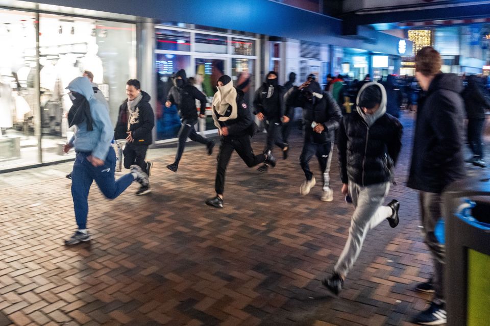 a group of people running in front of a store that says ' abercrombie & fitch ' on it