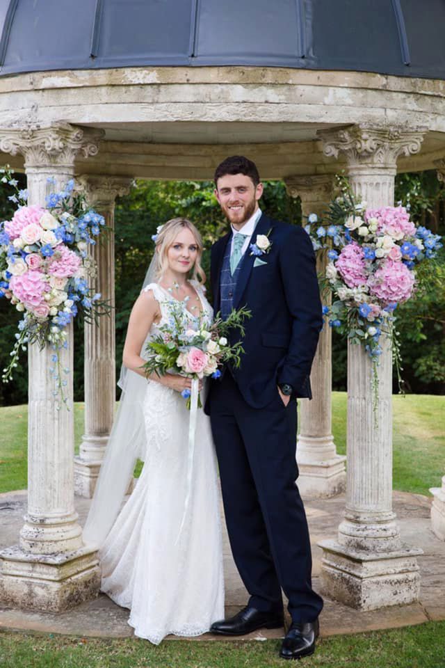 a bride and groom pose for a picture in front of a gazebo