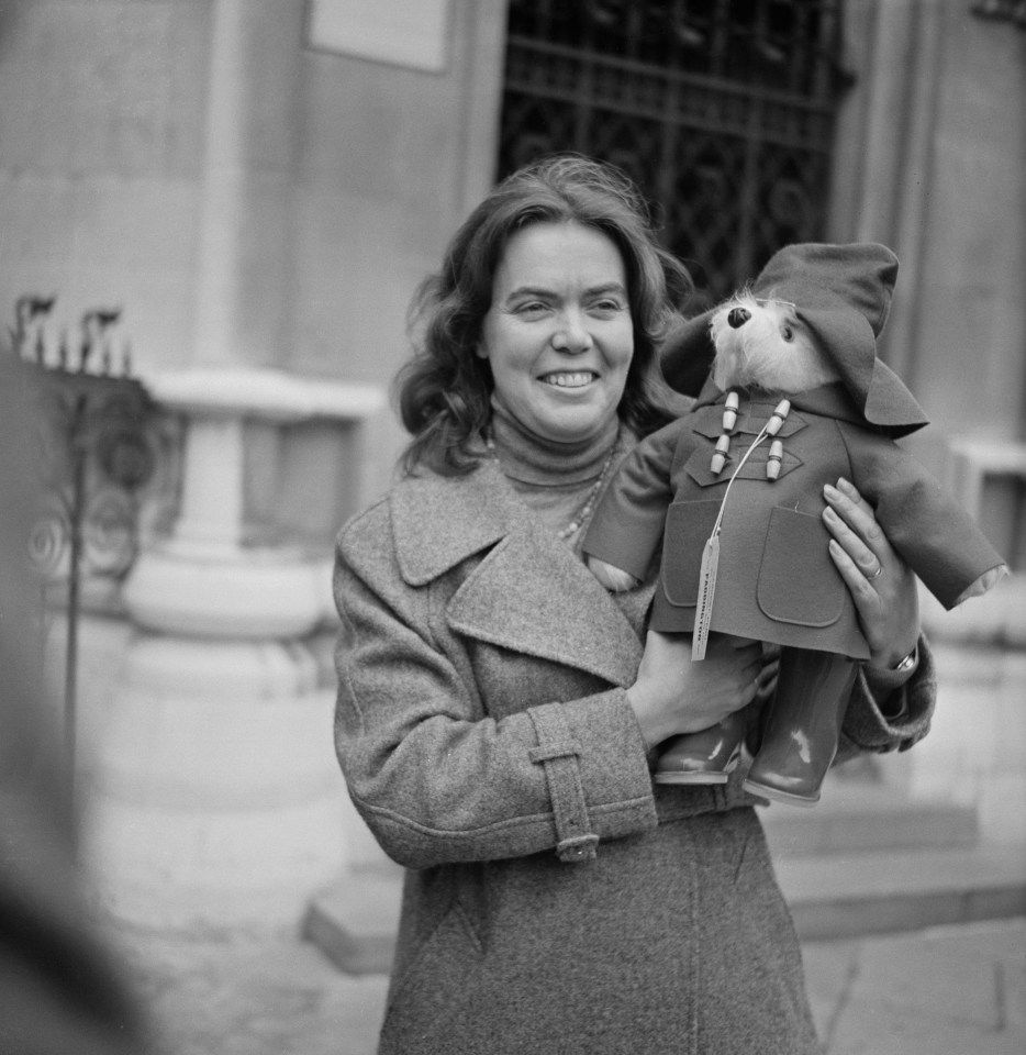 a woman holding a teddy bear with a tag that says ' paddington ' on it