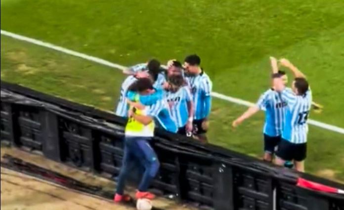 a group of soccer players are celebrating a goal on a soccer field .