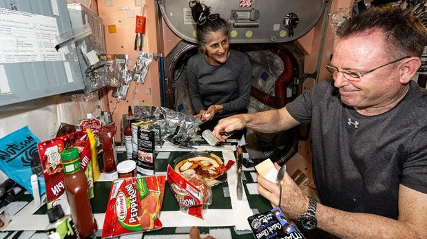 a man and a woman are preparing food in a space station .