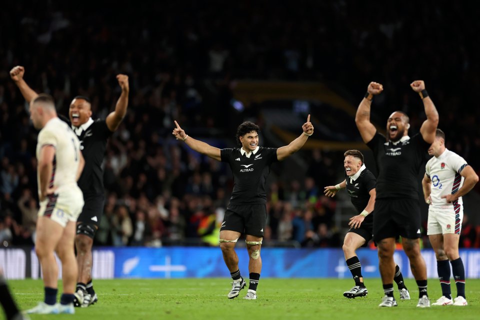a group of rugby players are celebrating on the field with their arms in the air