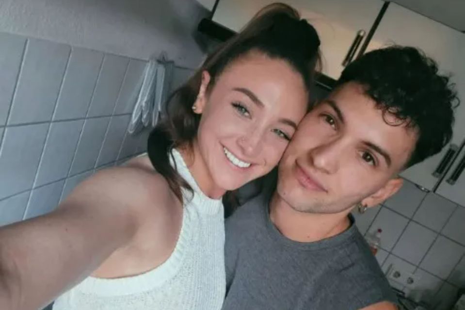 a man and a woman are posing for a selfie in a kitchen .