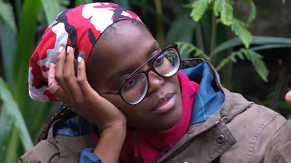 a woman wearing glasses and a headband rests her head on her hand