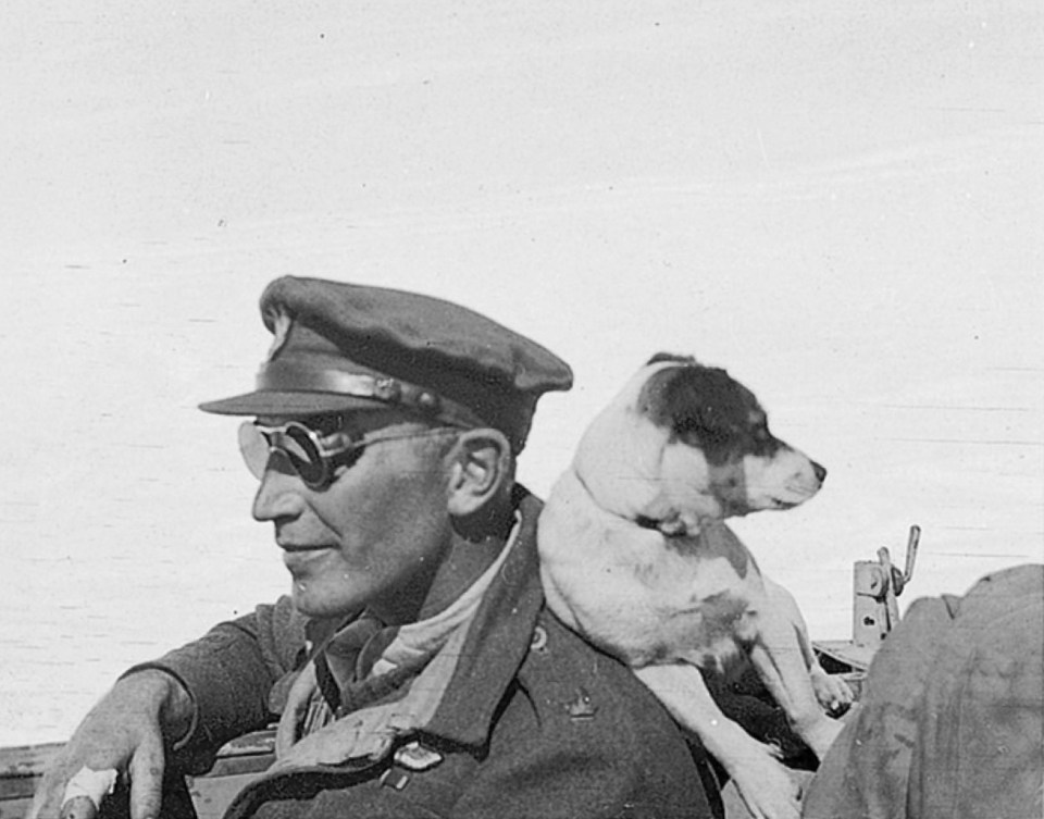 a black and white photo of a man with a dog on his shoulder
