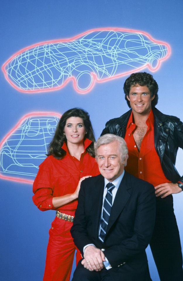 a man in a suit and tie sits next to a woman in a red jumpsuit