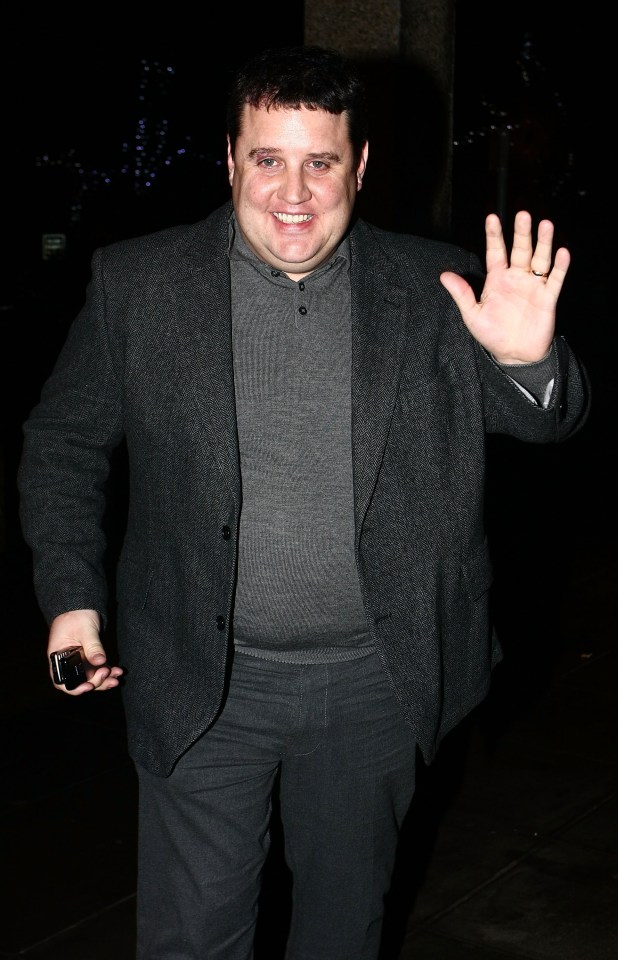 a man in a suit and sweater is waving his hand