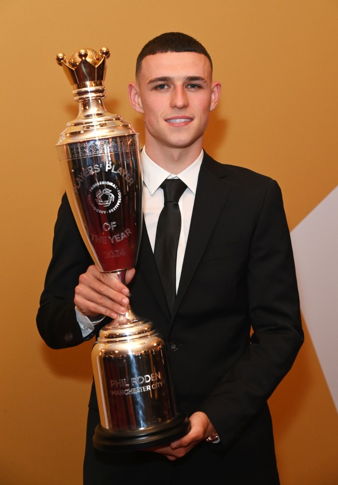 a man in a suit is holding a trophy that says manchester city