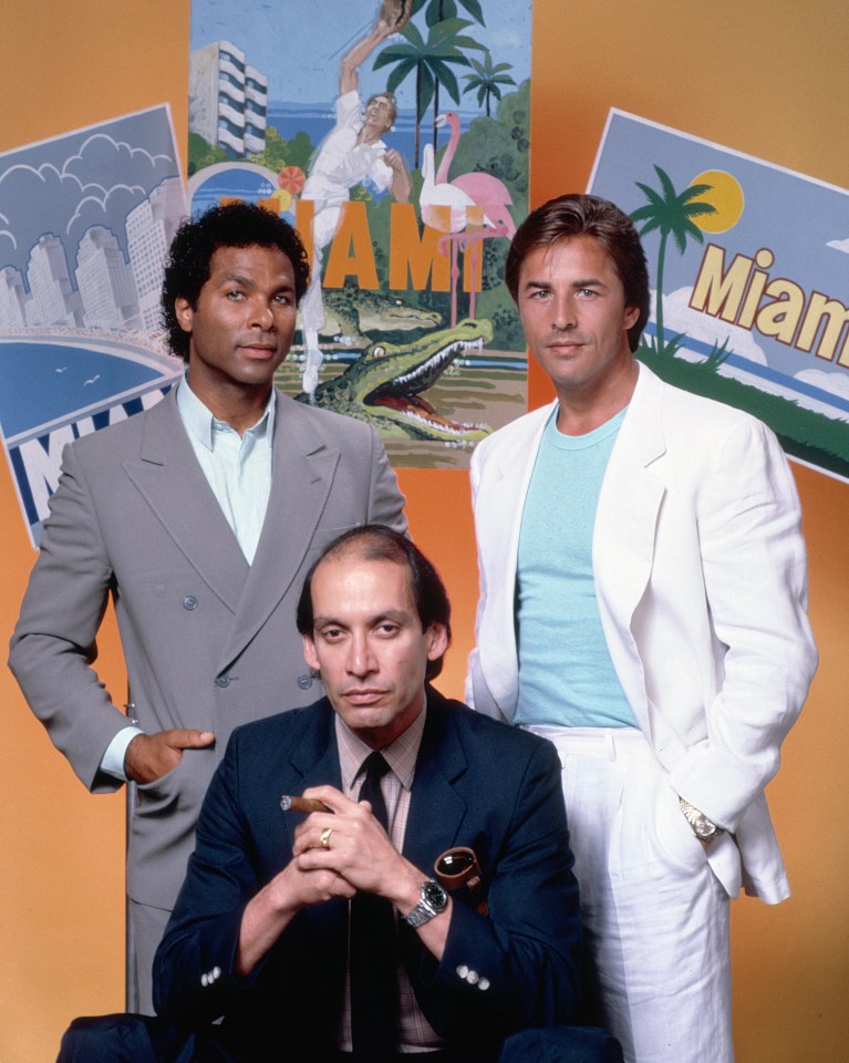 three men pose in front of a poster that says miami