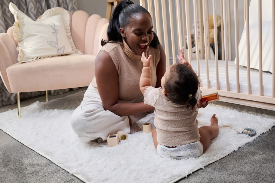 a woman is playing with a baby in a diaper