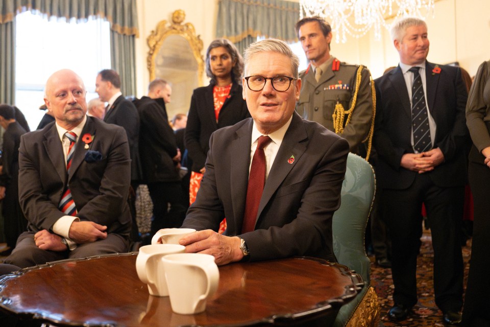 a man in a suit sits at a table with two cups on it