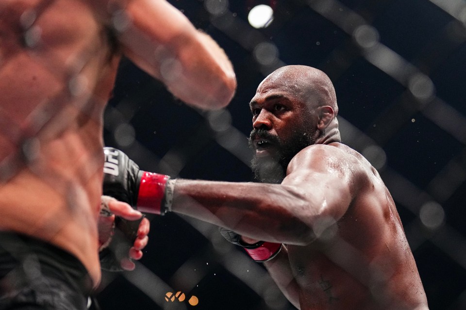 a man wearing a pair of ufc gloves is boxing another man