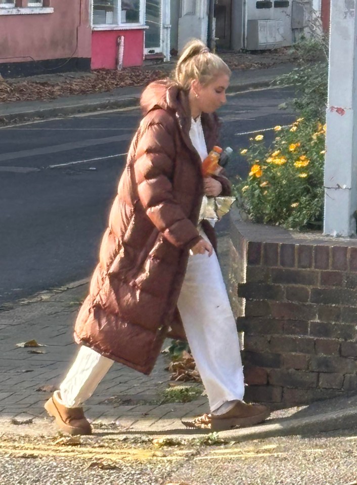 a woman in a long brown coat is walking down the street