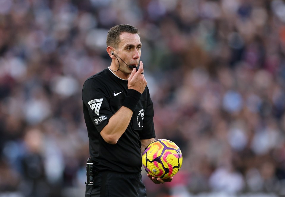 a referee holds a soccer ball while wearing a shirt that says no room for racism
