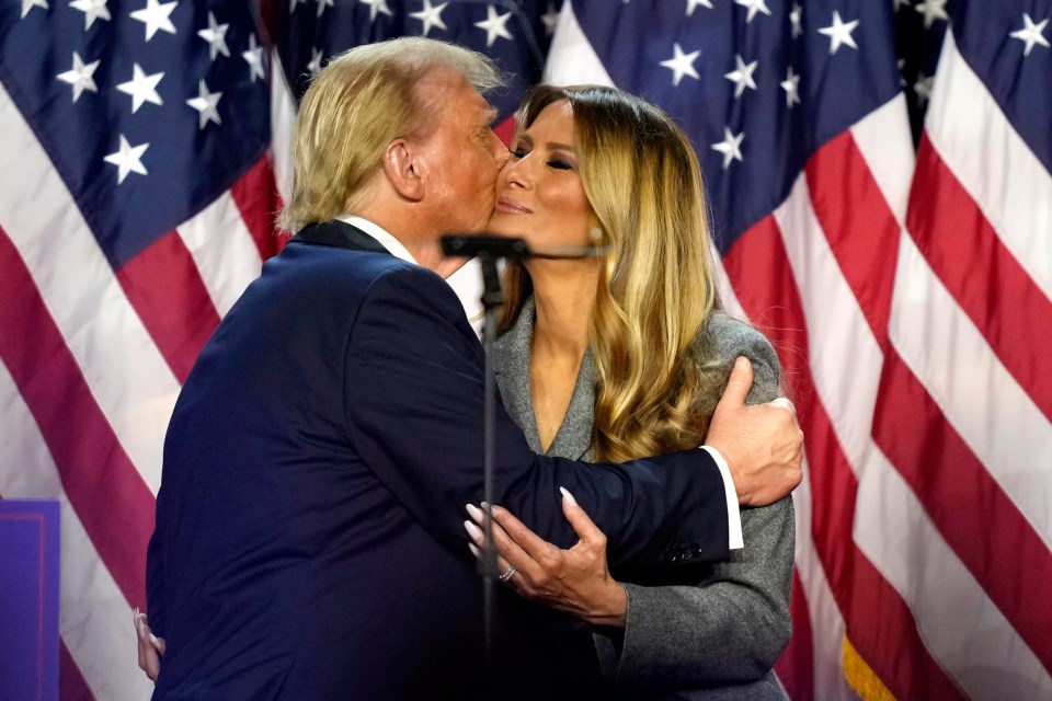 a man kisses a woman on the cheek in front of an american flag