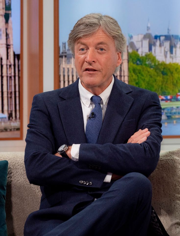 a man in a suit and tie sits on a couch with his arms crossed