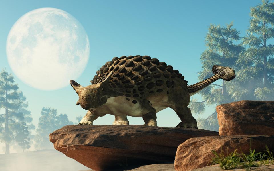 a dinosaur standing on a rock with a full moon in the background