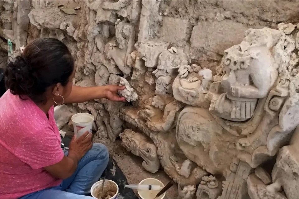 a woman in a pink shirt is working on a sculpture