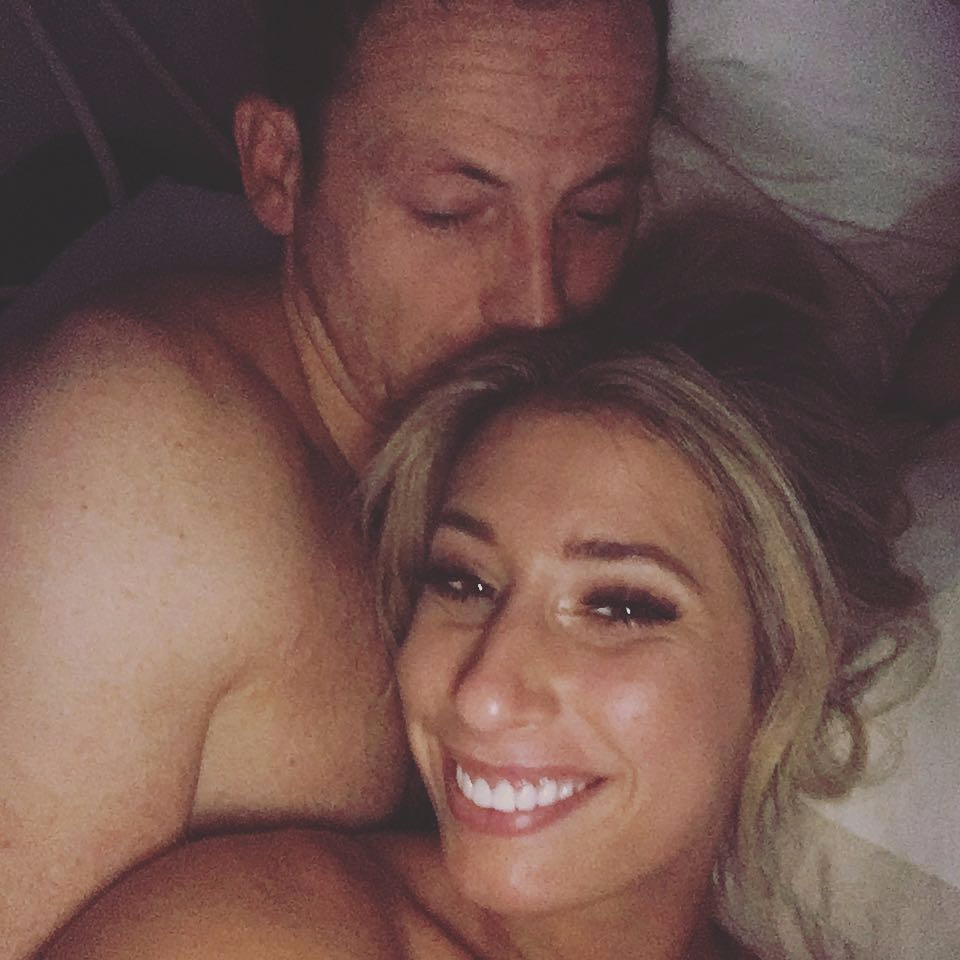 a shirtless man kisses a smiling woman on the cheek