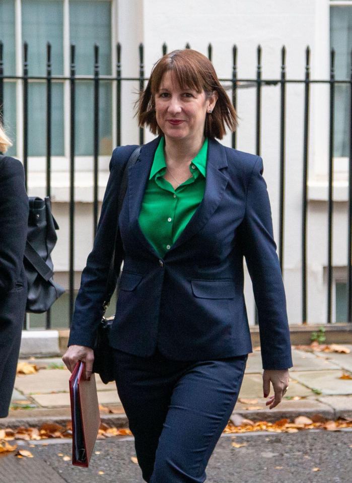 a woman in a suit and green shirt is walking down the street