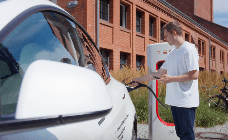 a man is charging an electric car at a tesla charging station