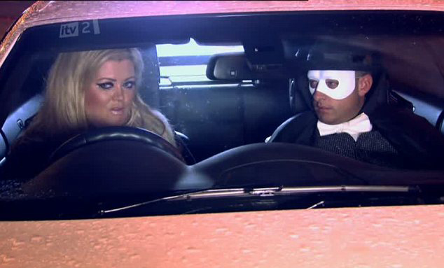 a man in a mask is driving a car next to a woman .