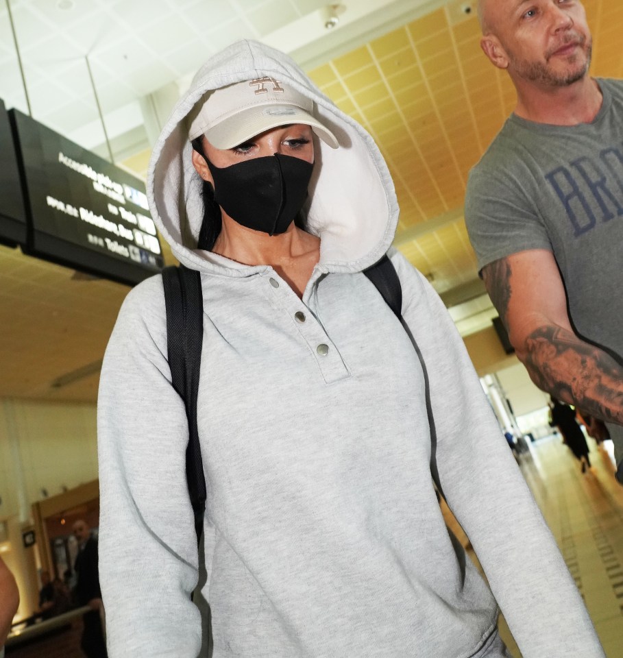 a woman wearing a grey hoodie and a white hat with the letter a on it