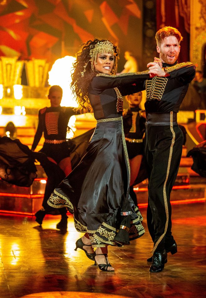 a woman in a black dress is dancing with a man