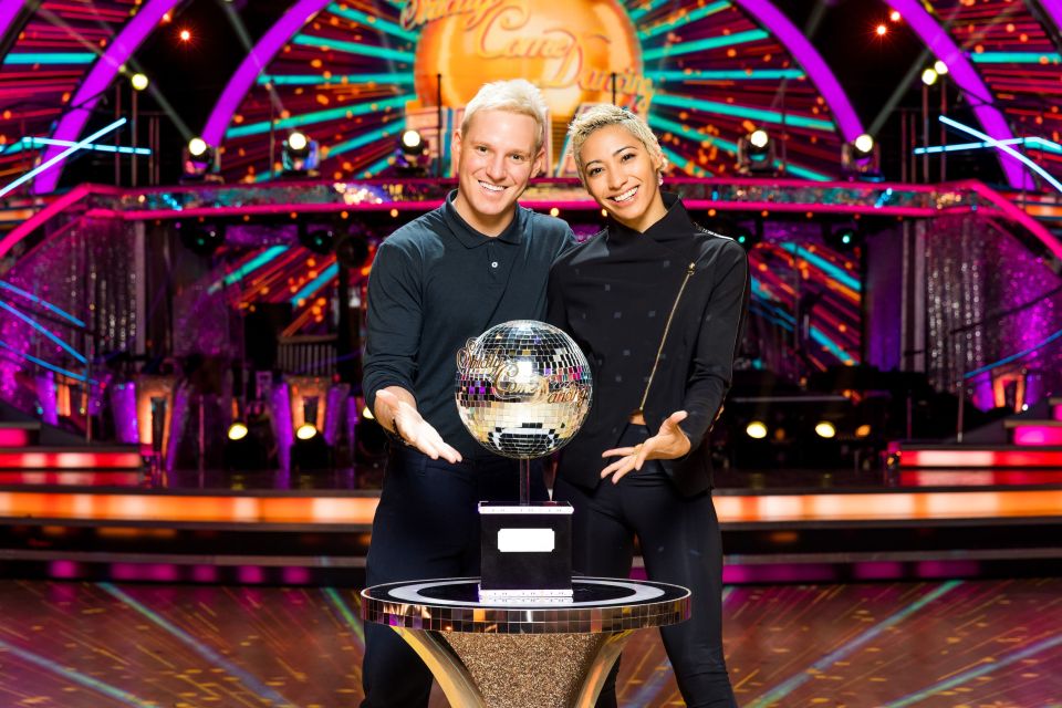 a man and a woman holding a disco ball in front of a stage that says strictly come dancing