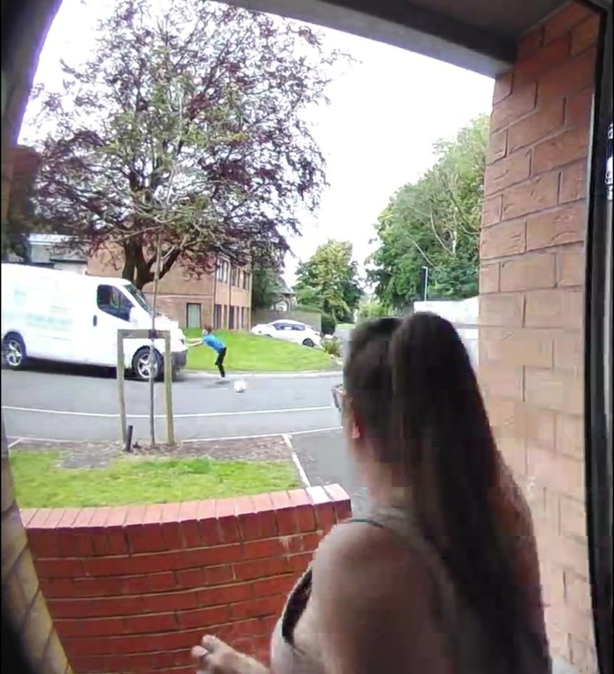 a woman is looking out a window at a boy kicking a soccer ball