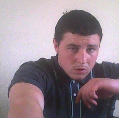 a man in a black shirt is taking a selfie with his hand on his chin .