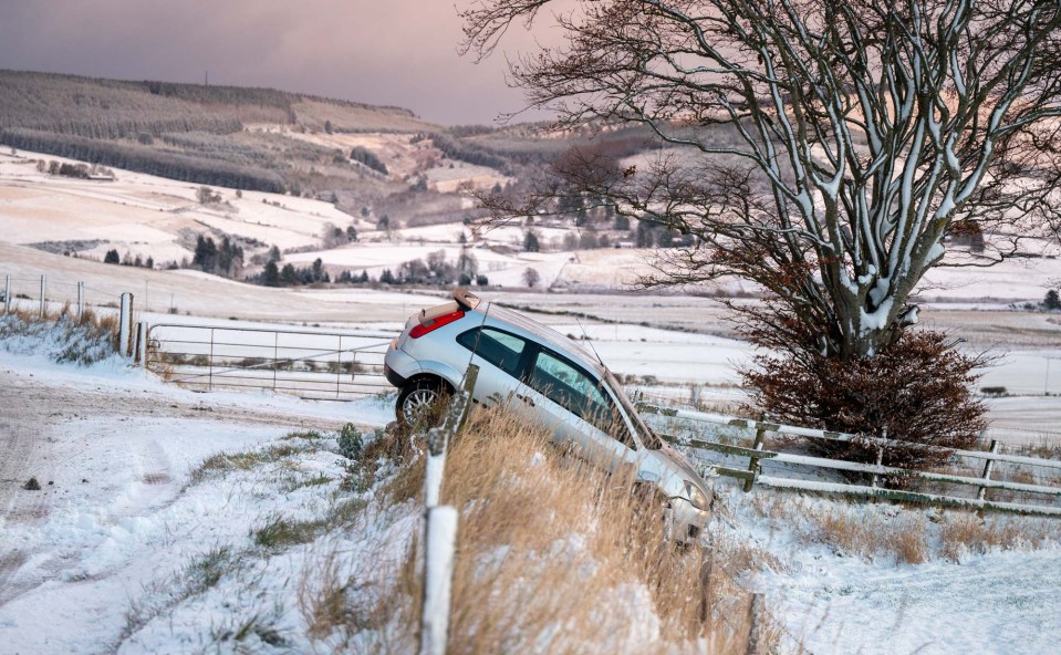 a car that has fallen off the road in the snow