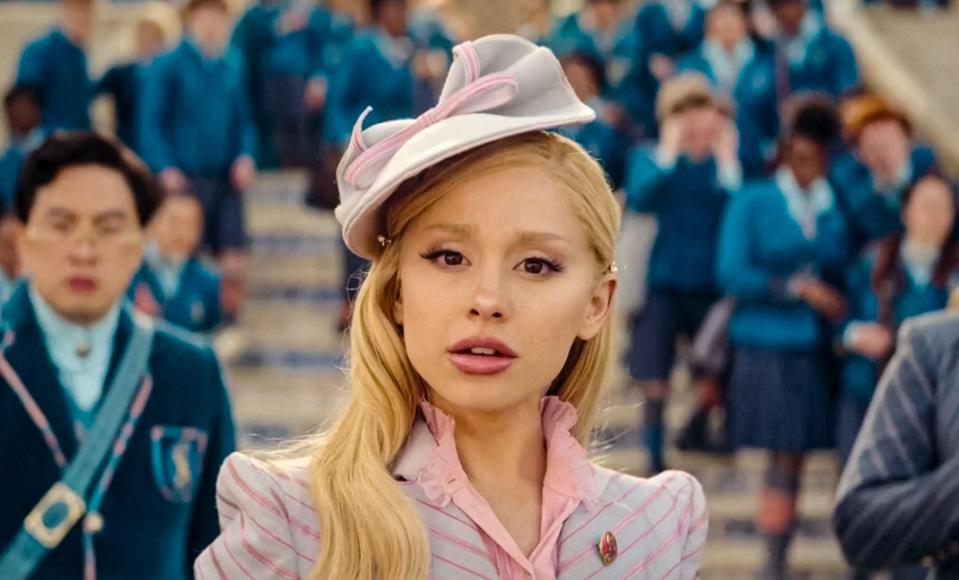 a woman wearing a pink and white hat stands in front of a crowd of people